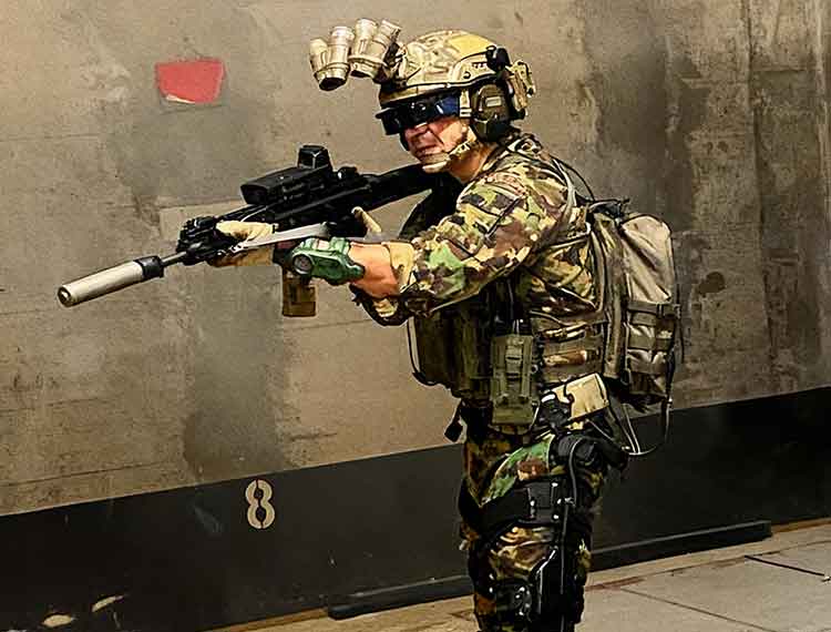 Operator in the aiming position wearing goggles, with the haptic sleeve on the forearm